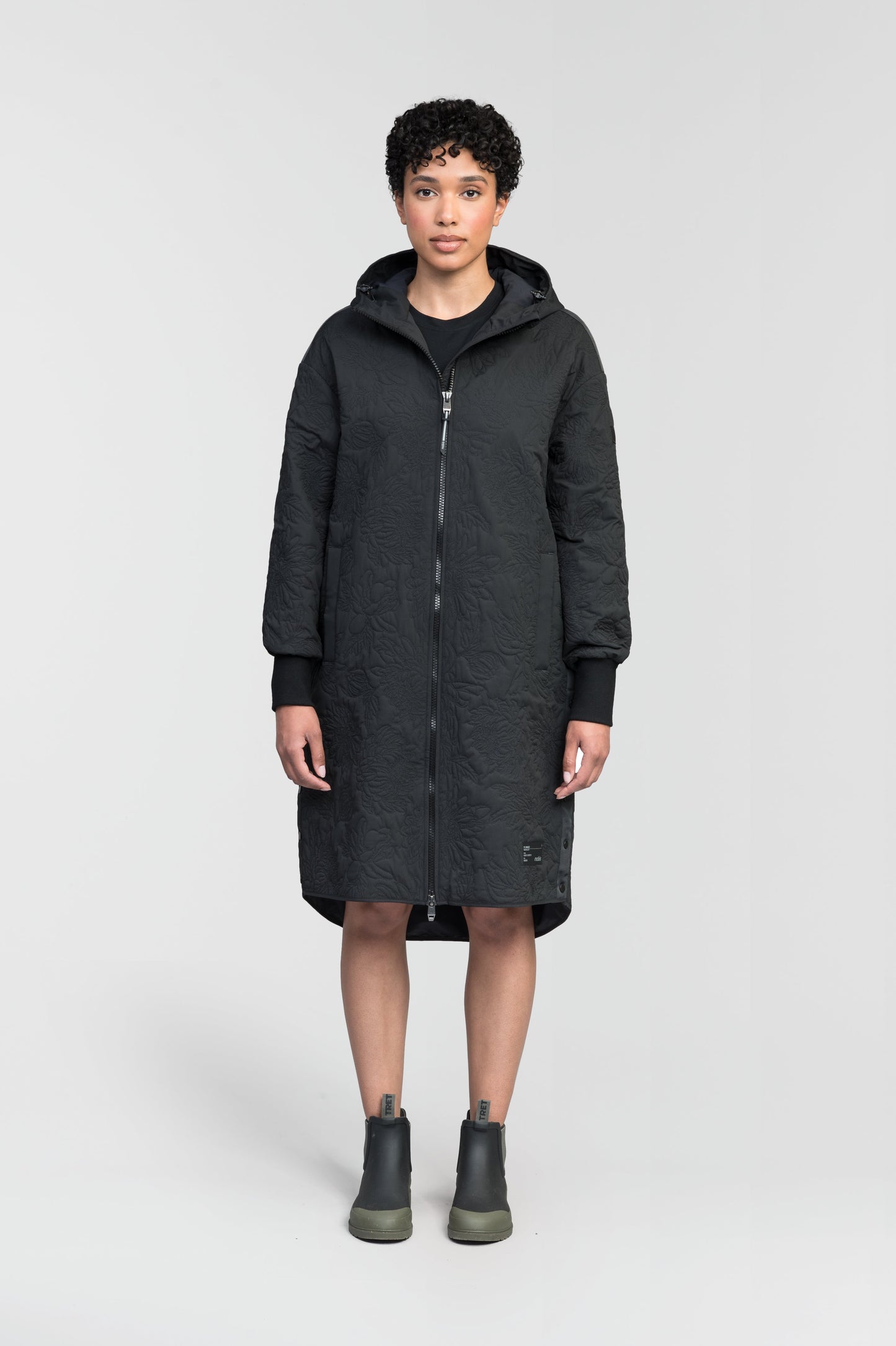 Surrey Women's Performance Quilted Long Mid Layer Jacket in knee length, Primaloft Gold Insulation Active+, non-removable hood, single welt magnetic closure pockets, ribbed cuffs, two-way centre front zipper, grosgrain ribbon detail and shoulders and side seam, and snap closure side seam vents, in Black