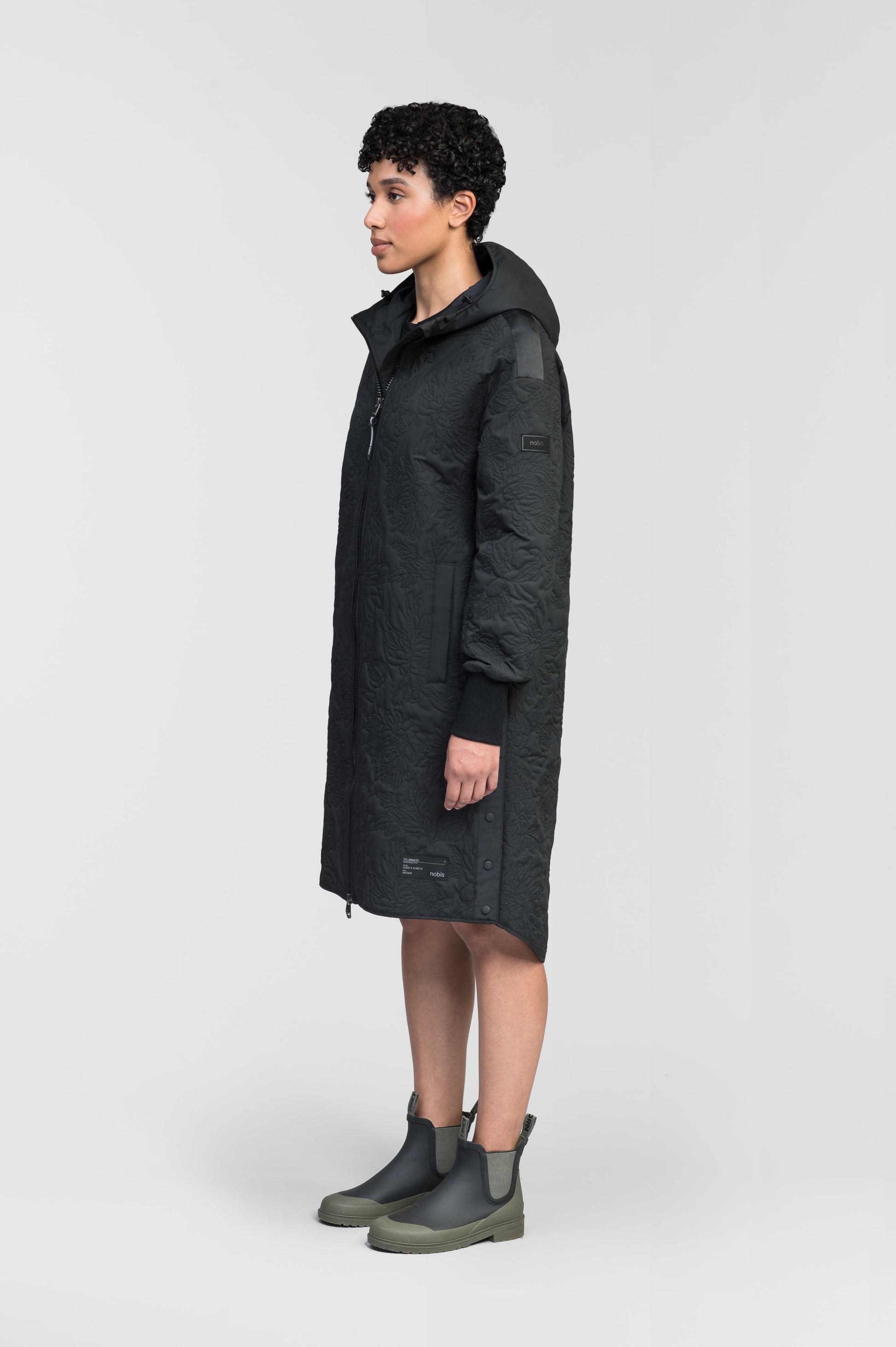 Surrey Women's Performance Quilted Long Mid Layer Jacket in knee length, Primaloft Gold Insulation Active+, non-removable hood, single welt magnetic closure pockets, ribbed cuffs, two-way centre front zipper, grosgrain ribbon detail and shoulders and side seam, and snap closure side seam vents, in Black