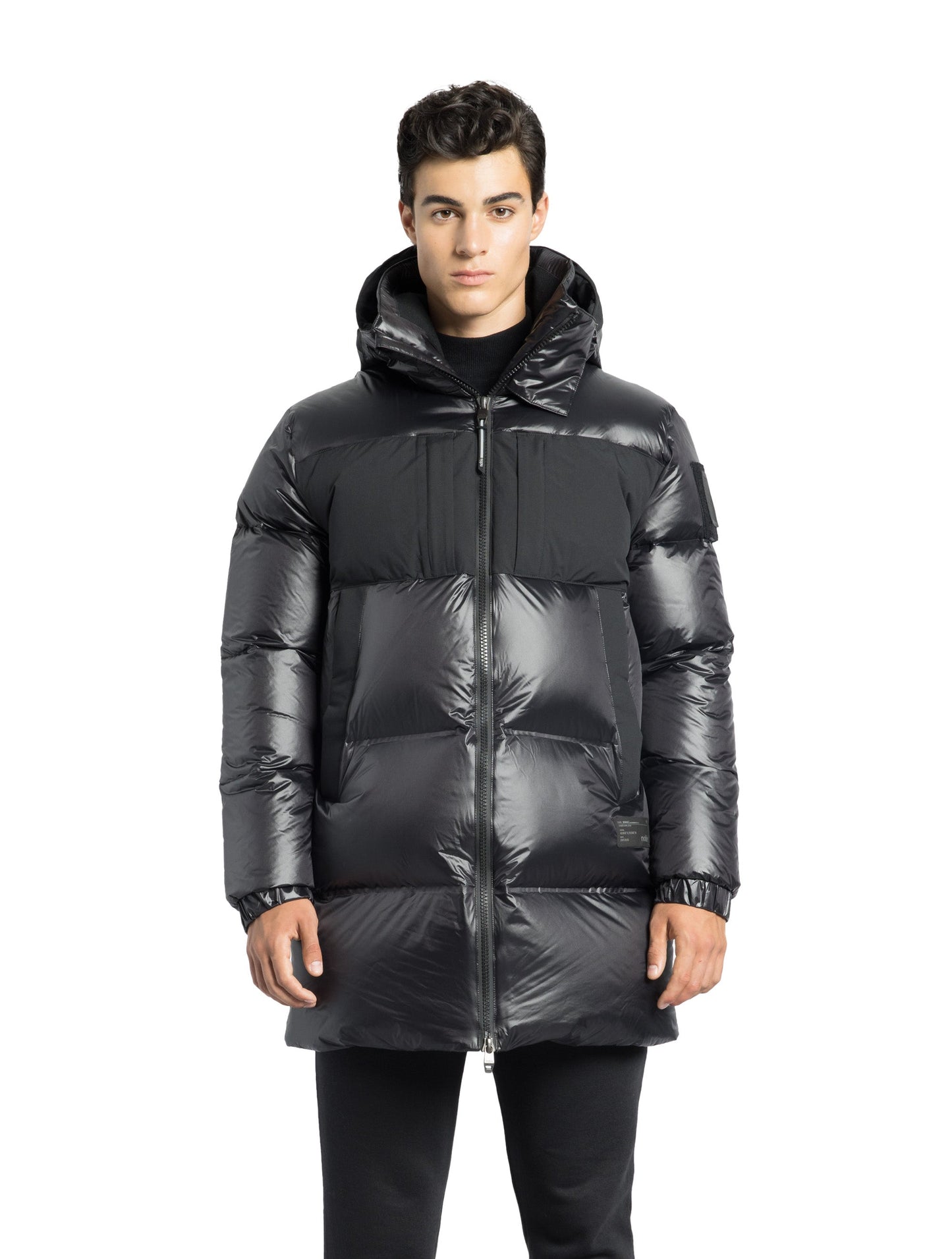 Neelix Men's Long Puffer Jacket in thigh length, premium cire technical nylon taffeta and stretch ripstop fabrication, Premium Canadian origin White Duck Down insulation, non-removable down-filled hood, two-way centre-front zipper, pit zipper vents, hidden chest zipper pockets, fleece-lined magnetic closure waist pockets, in Black